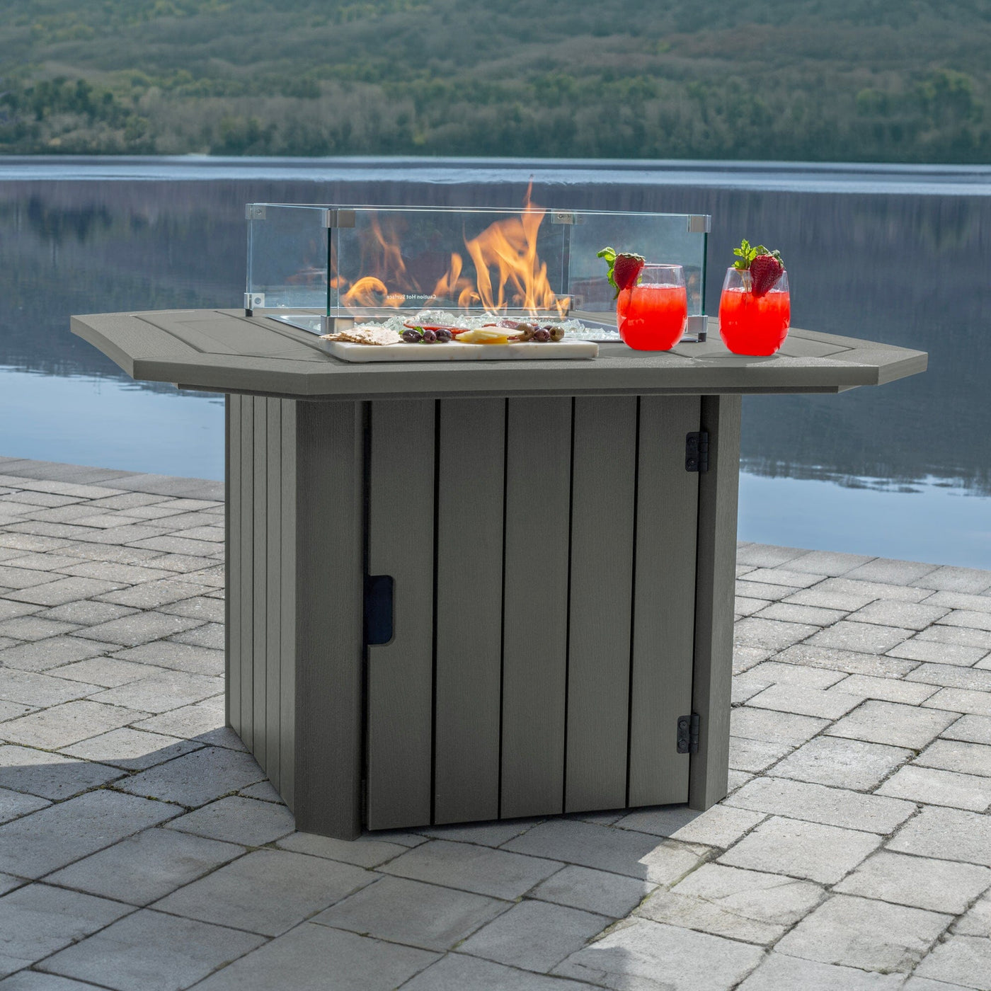 Gray Oasis Fire Table with lit flame and lake in background