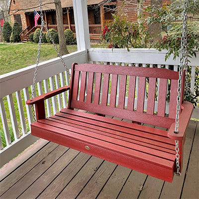 Red Lehigh porch swing on white porch. 