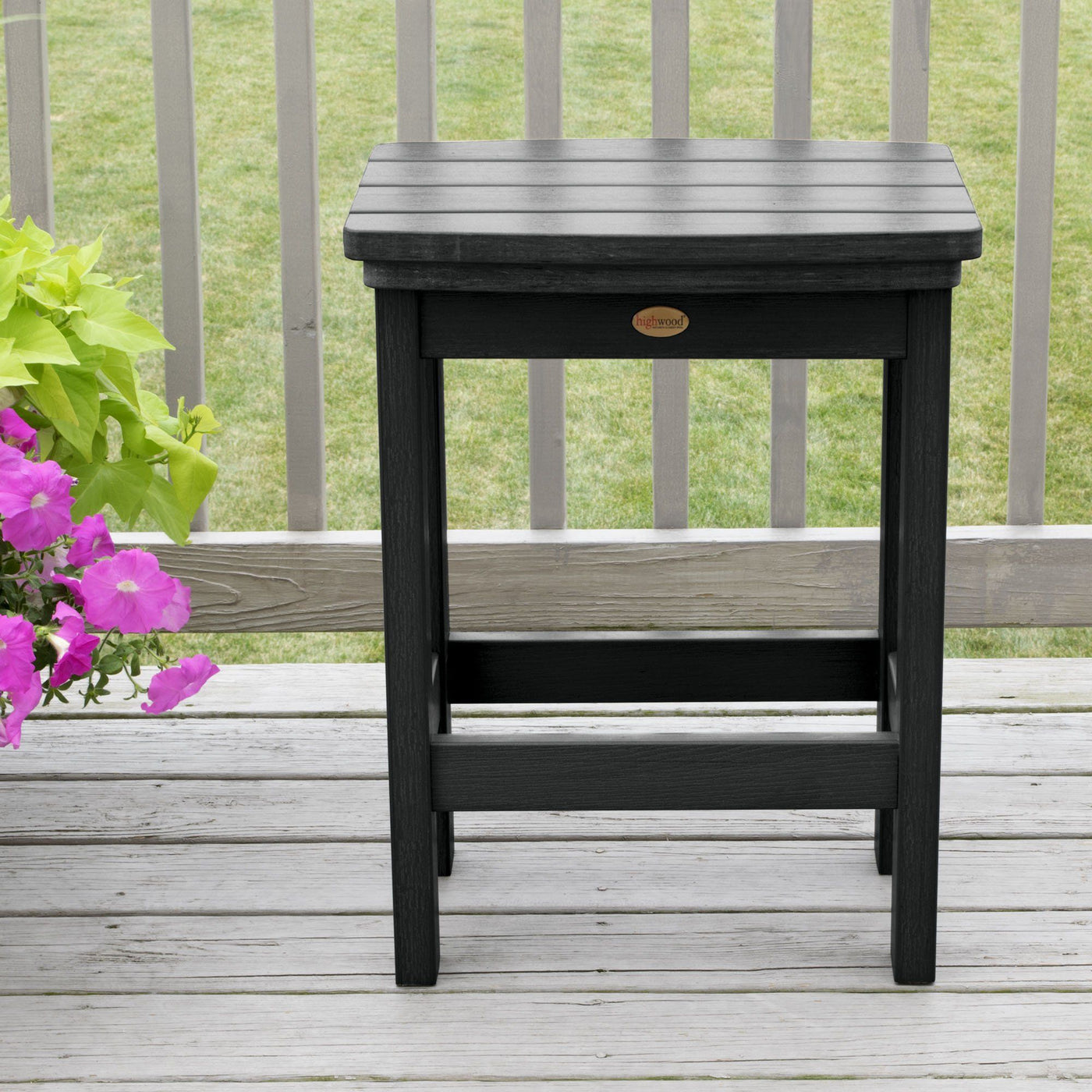 Black Lehigh counter height stool on deck with flowers in background