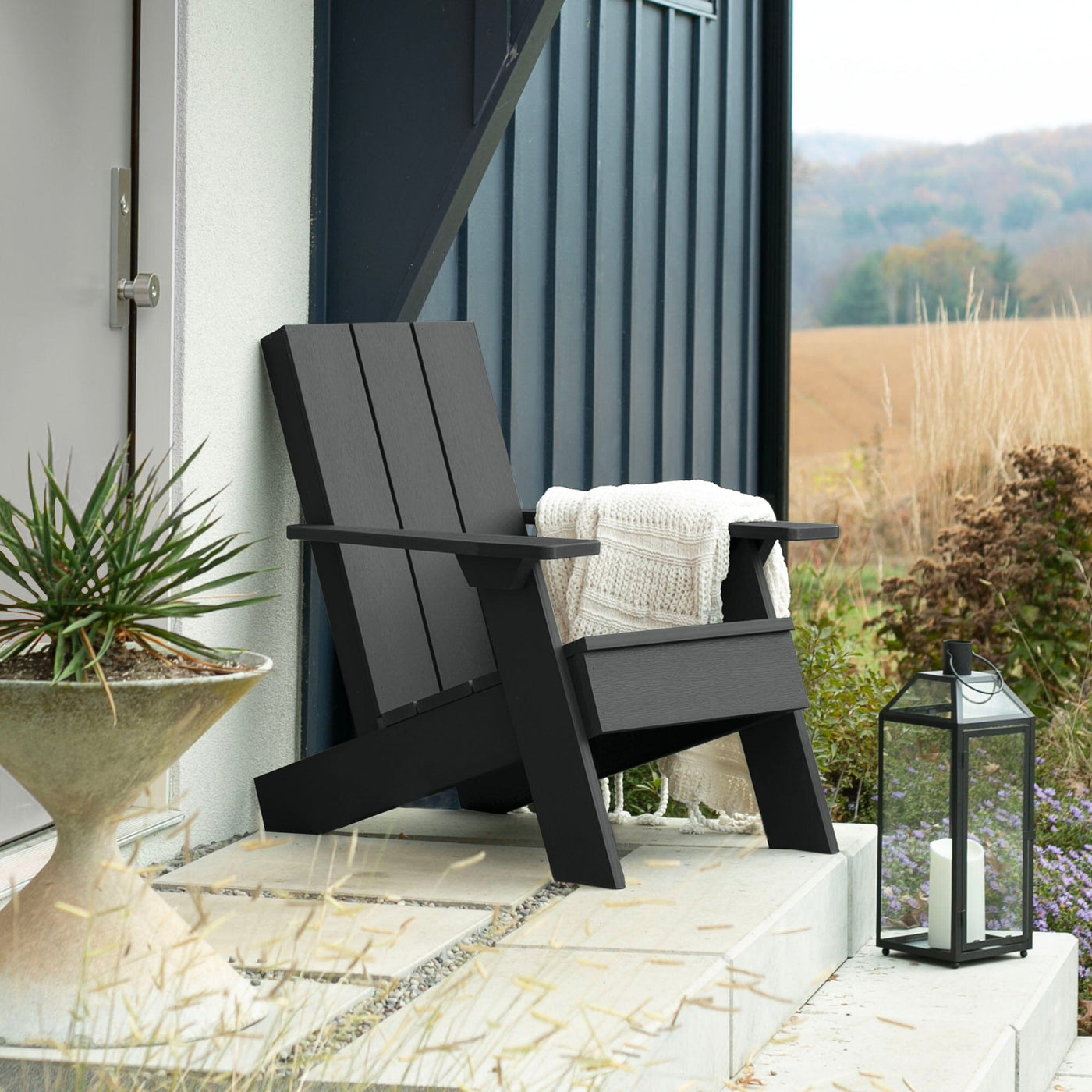 Black Italica Modern Adirondack chair on porch with blanket and lantern