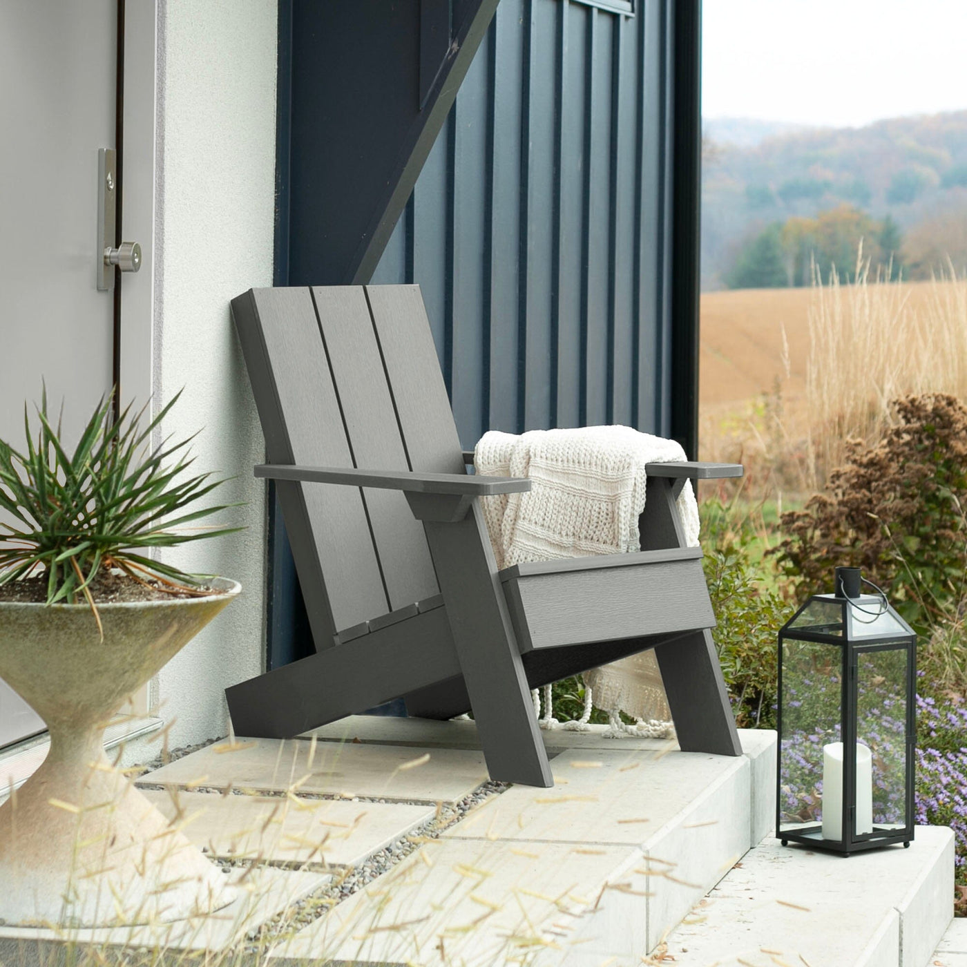 Gray Italica Modern Adirondack chair on porch with blanket and lantern