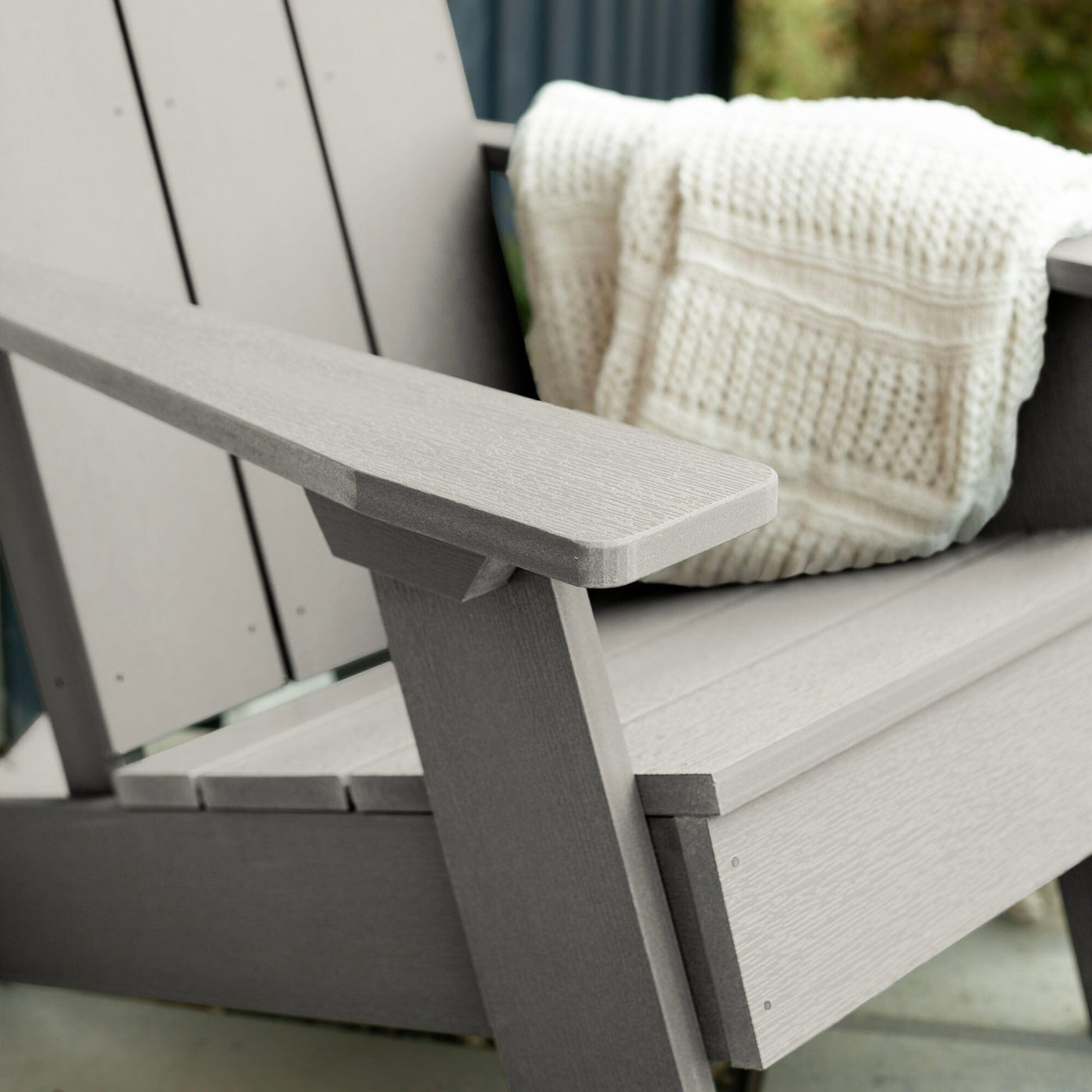 Close up of light gray Italica Modern Adirondack Chair with blanket