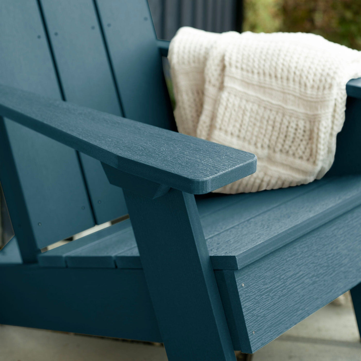 Close up of Blue Italica Modern Adirondack Chair with blanket