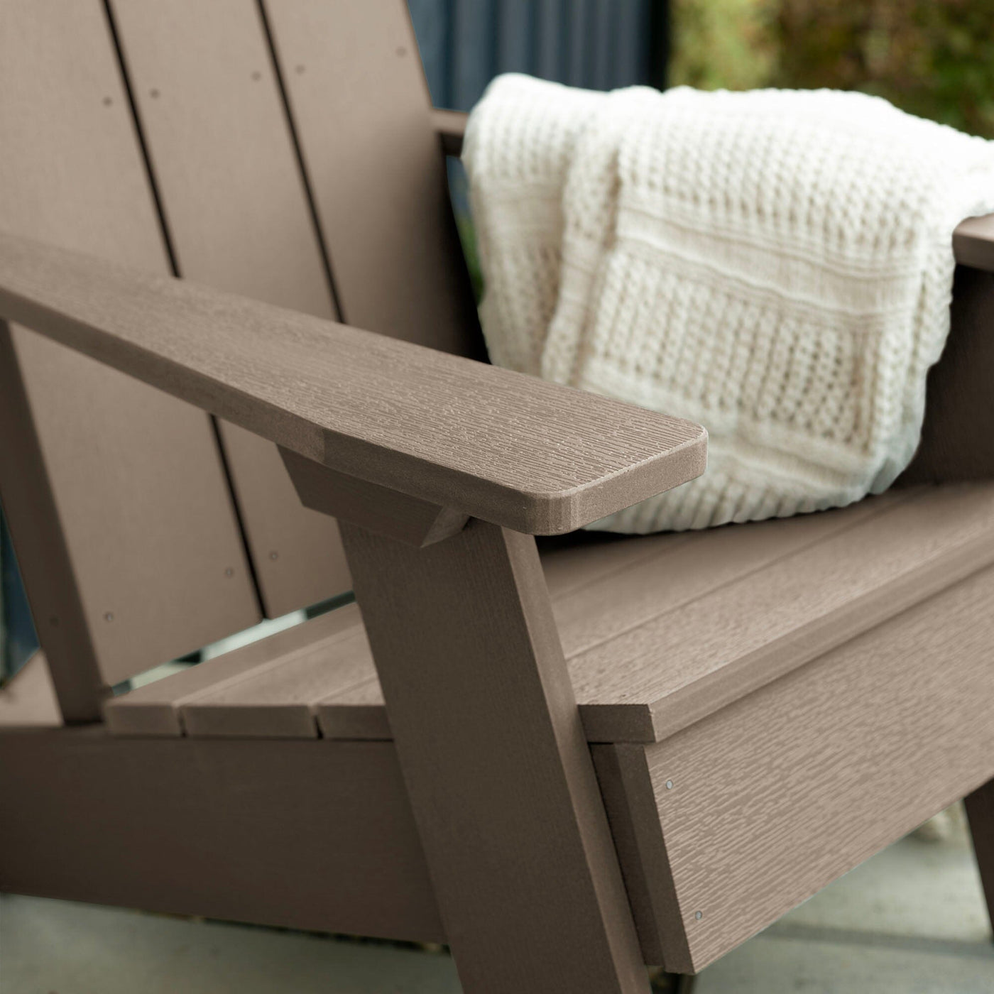 Close up of light brown Italica Modern Adirondack Chair with blanket
