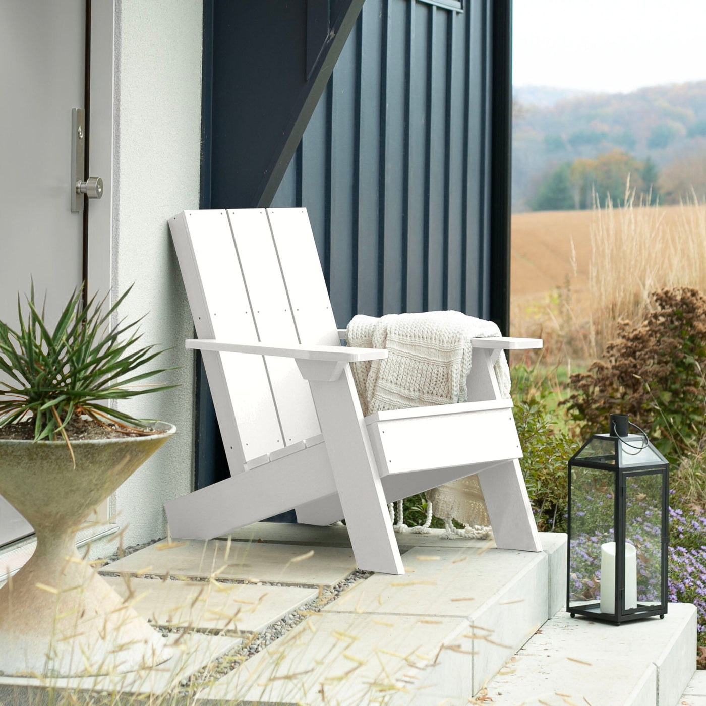 White Italica Modern Adirondack chair on porch with blanket and lantern