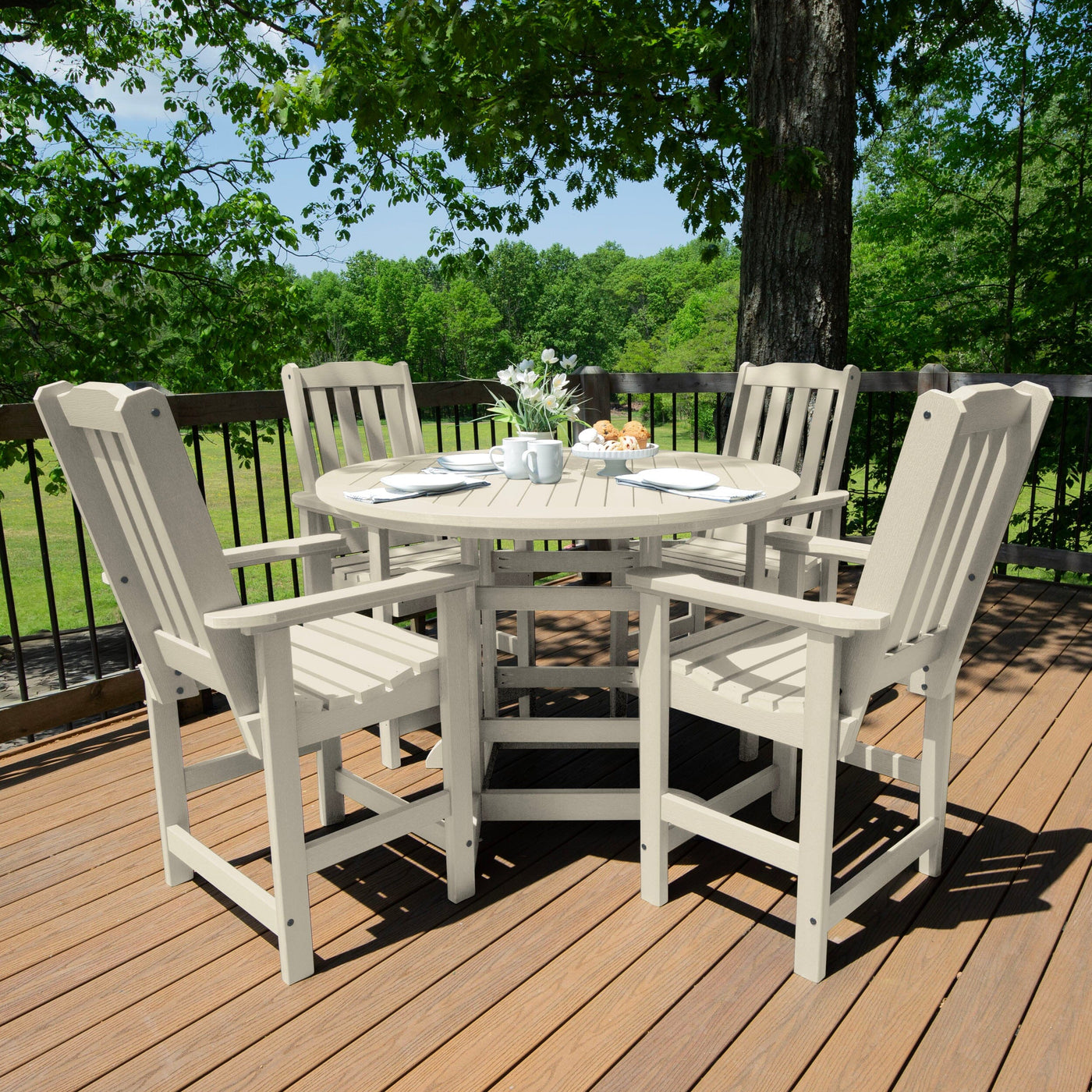 Beige round dining set on deck with greenery