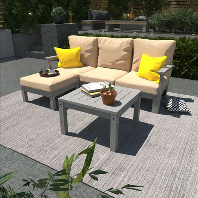 Deep Seating Sofa, Ottoman, and side table set with gray frames and beige cushions in stone outdoor area. 