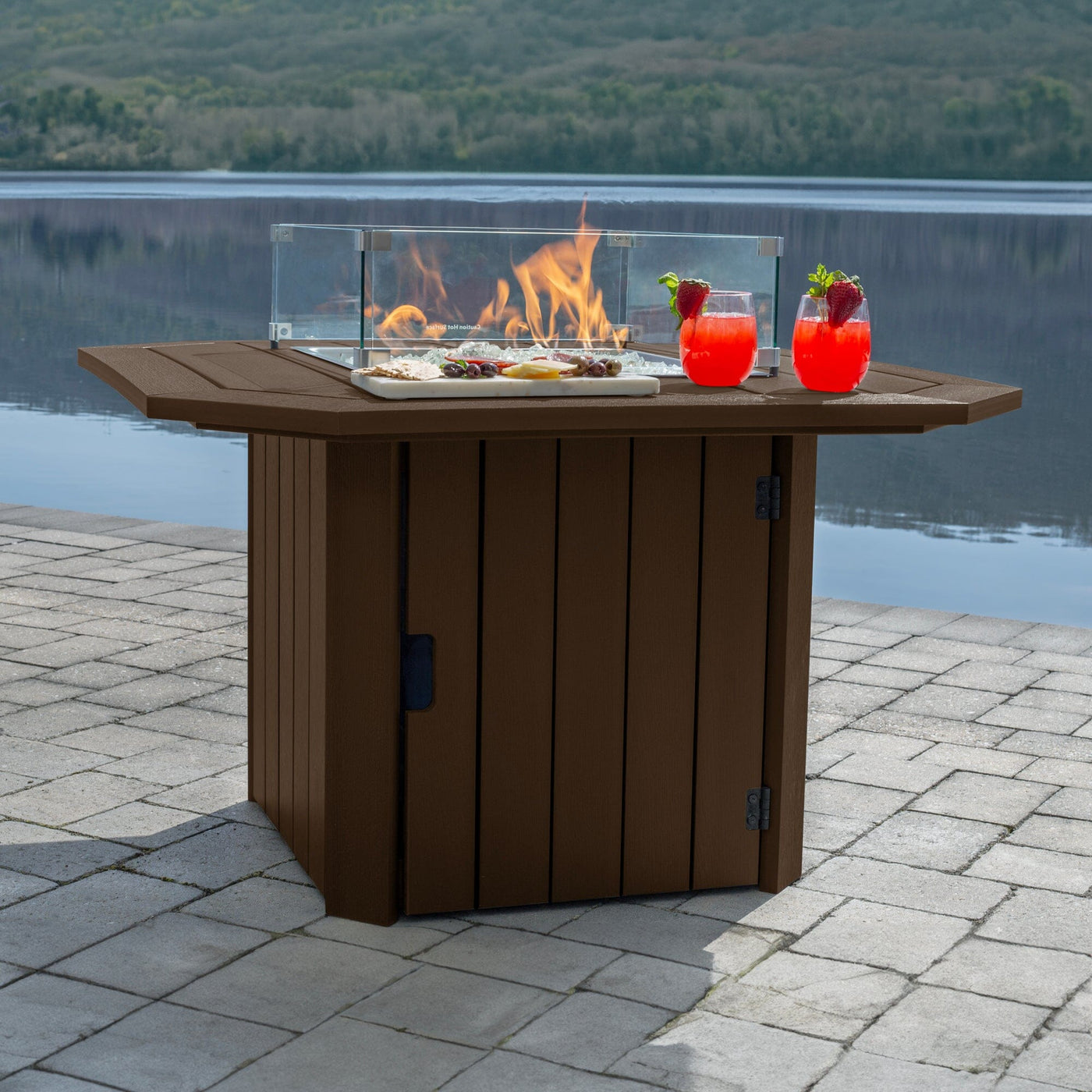 Brown Oasis Fire Table with lit flame and lake in background