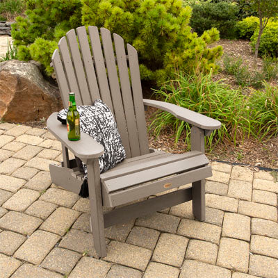 Light brown king sized Hamilton Adirondack chair on paved stone with beer and pillow. 