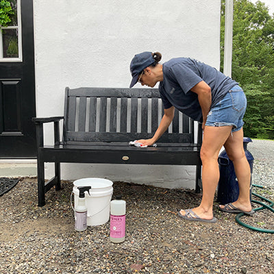 Woman cleaning black Lehigh bench. 