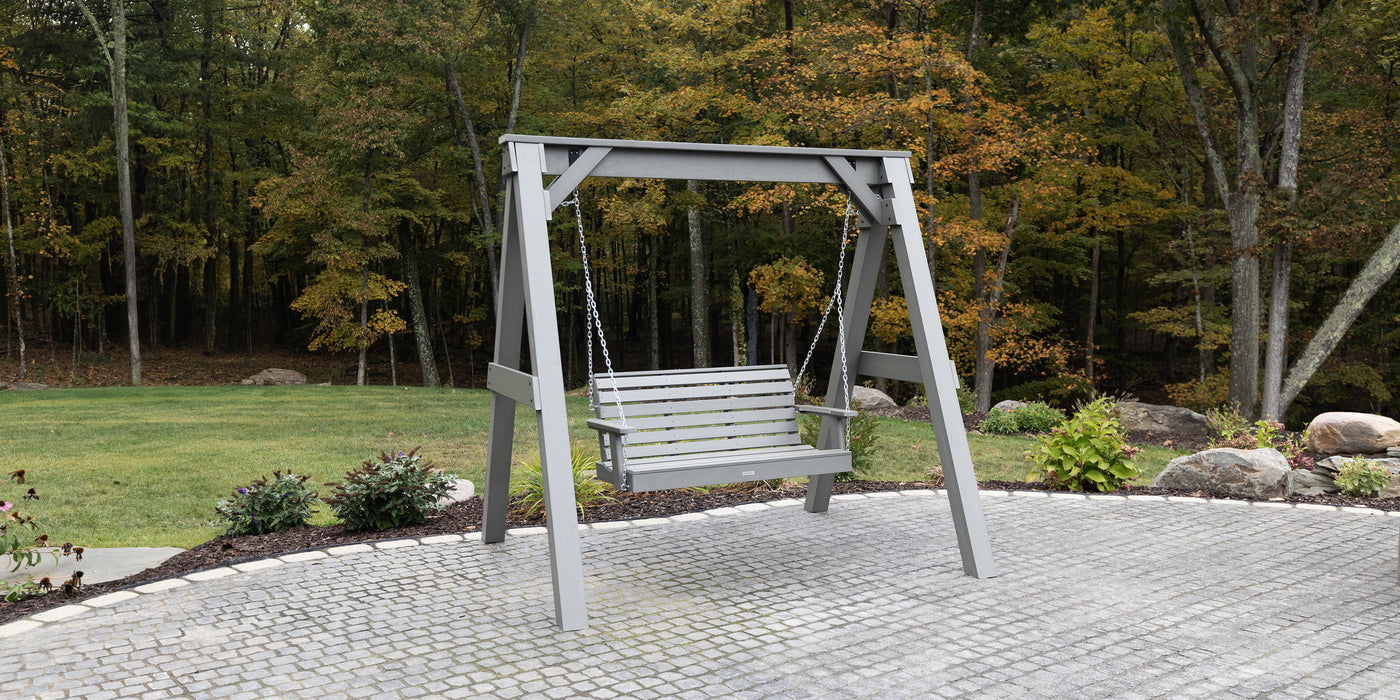Poly lumber swing bench  set in a garden setting with trees and grass in the background