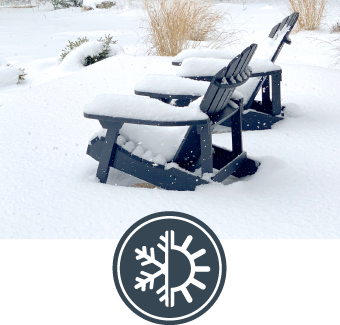 Two Adirondack chairs covered in snow in a winter landscape.