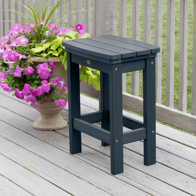 Dark blue Lehigh counter height stool on deck with flowers in background