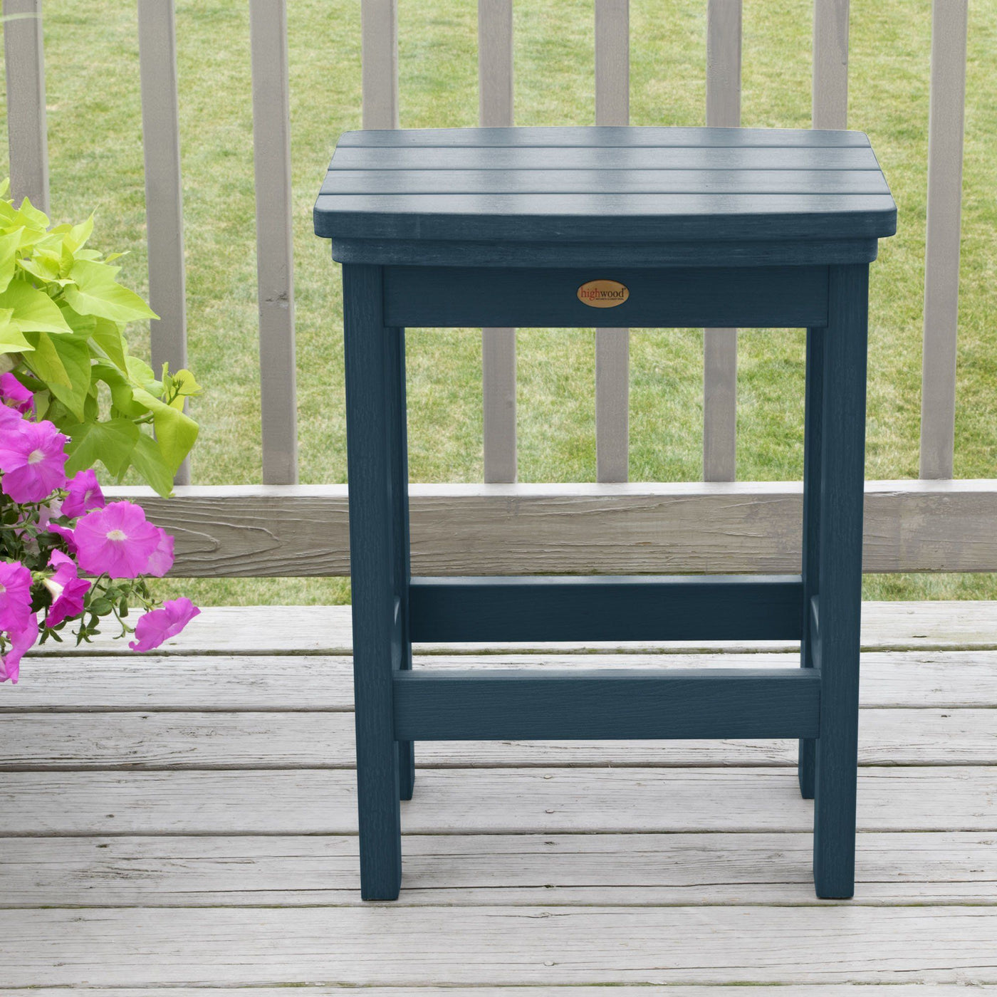 Light blue Lehigh counter height stool on deck with flowers in background