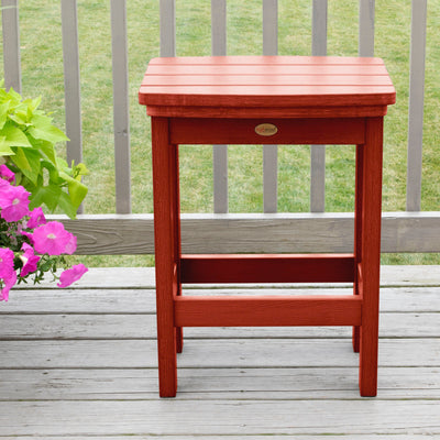 Red Lehigh counter height stool on deck with flowers in background