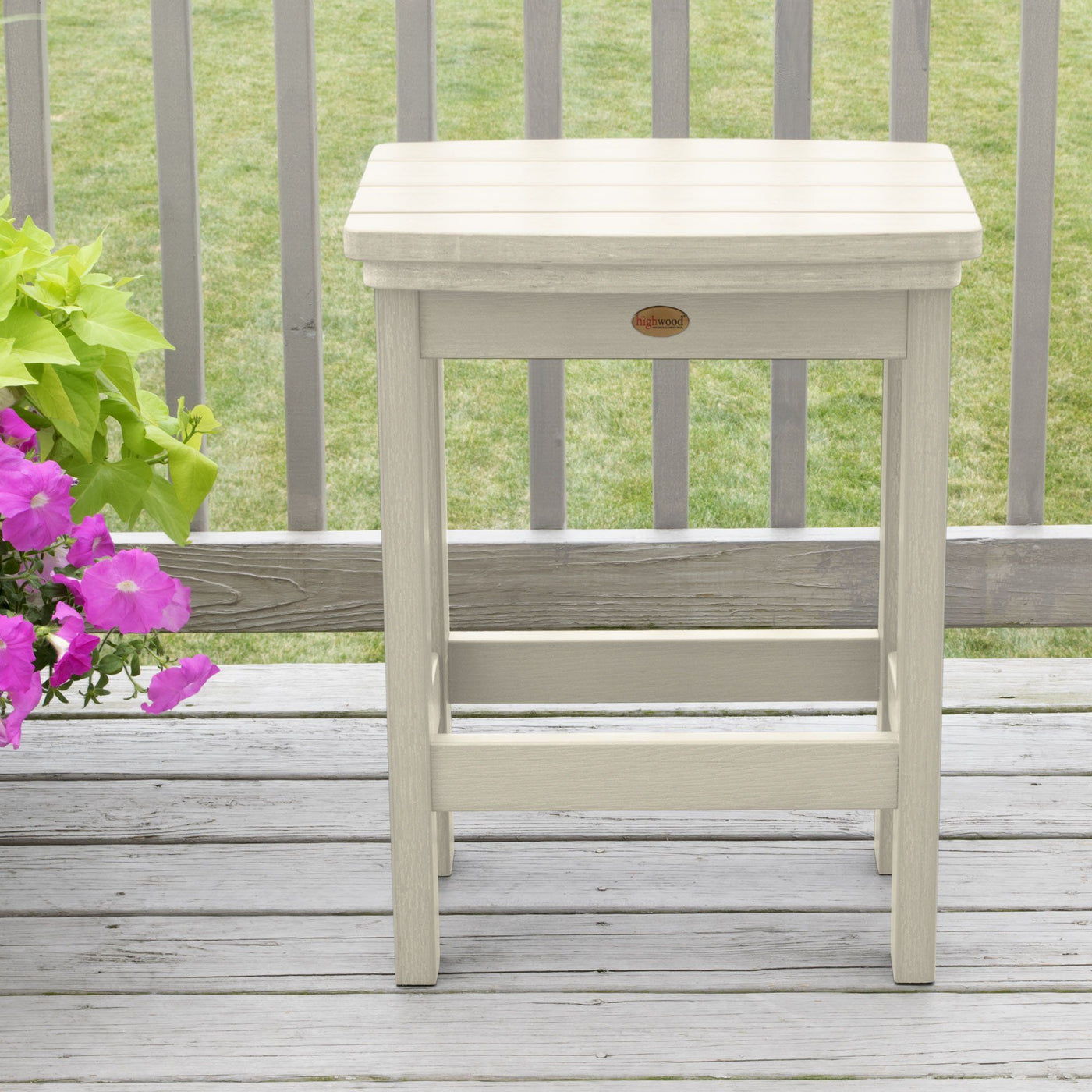 Whitewash Lehigh counter height stool on deck with flowers in background