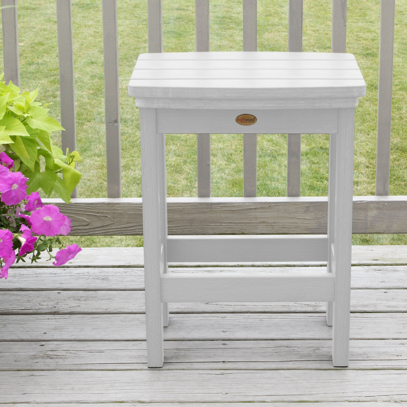 White Lehigh counter height stool on deck with flowers in background