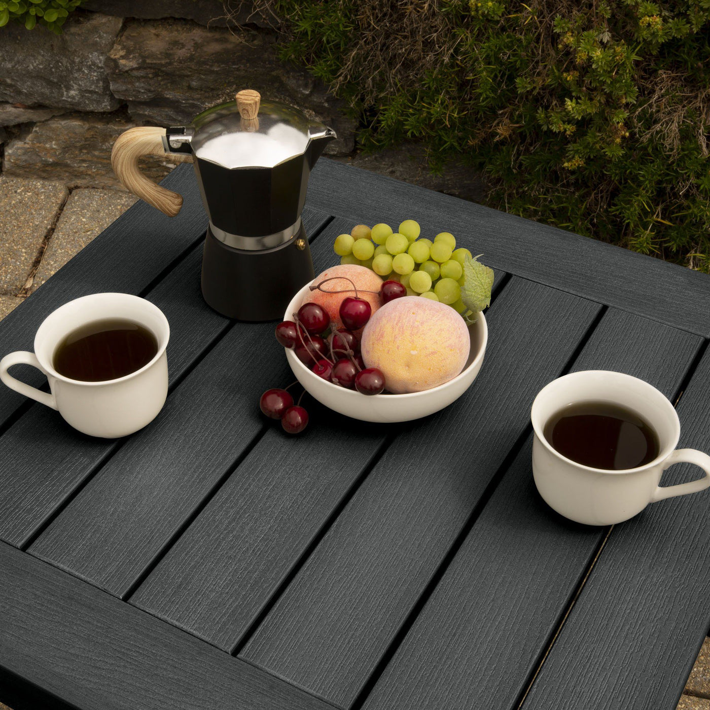 Table with fruit and coffee cups on patio