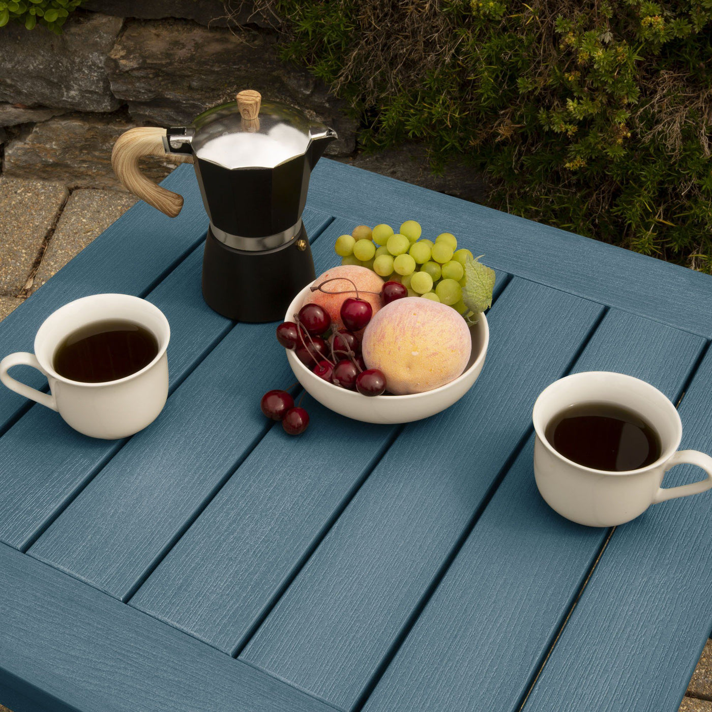 Table surface with cups and fruit on blue chair